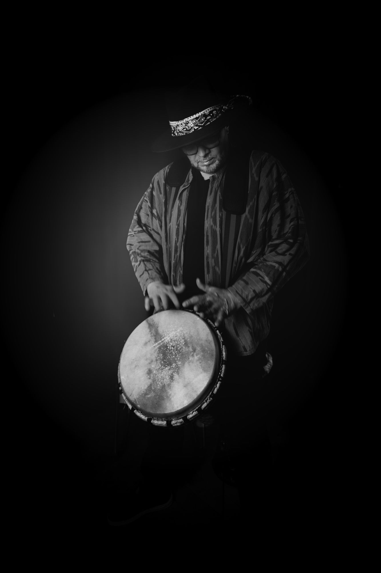 Master M playing djembé in a spotlight