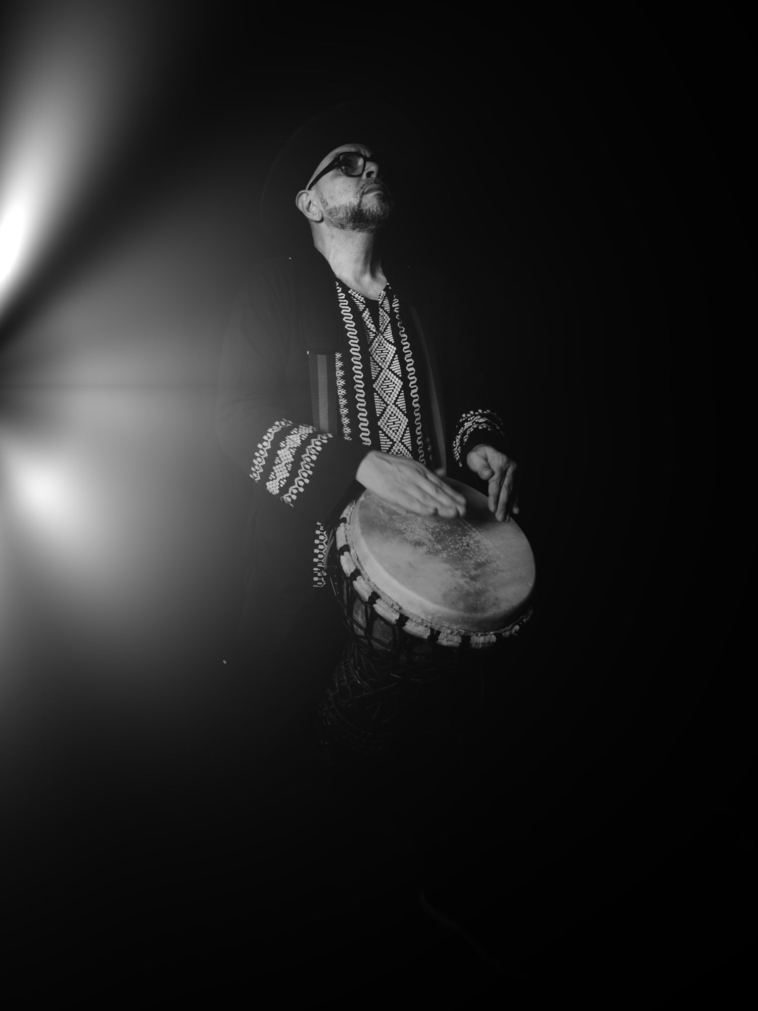Master M looking up, playing djembé