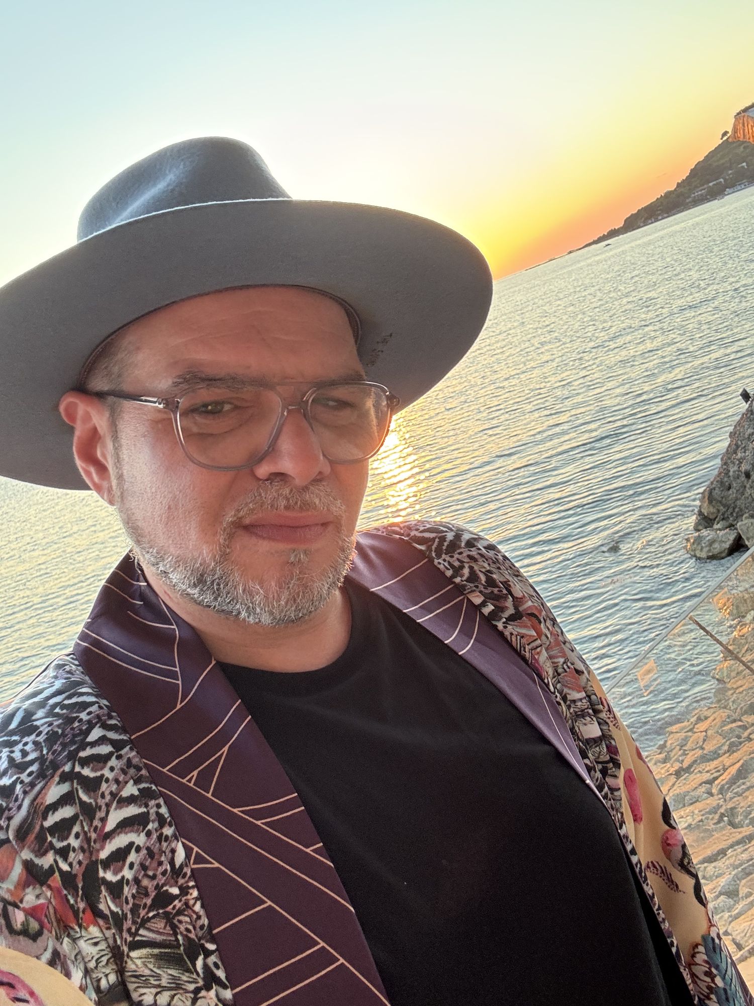 Master M in a hat, at sunset by the sea