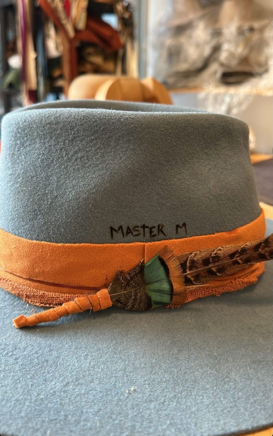 Master M hat with the name burned into the felt, orange band and feathers